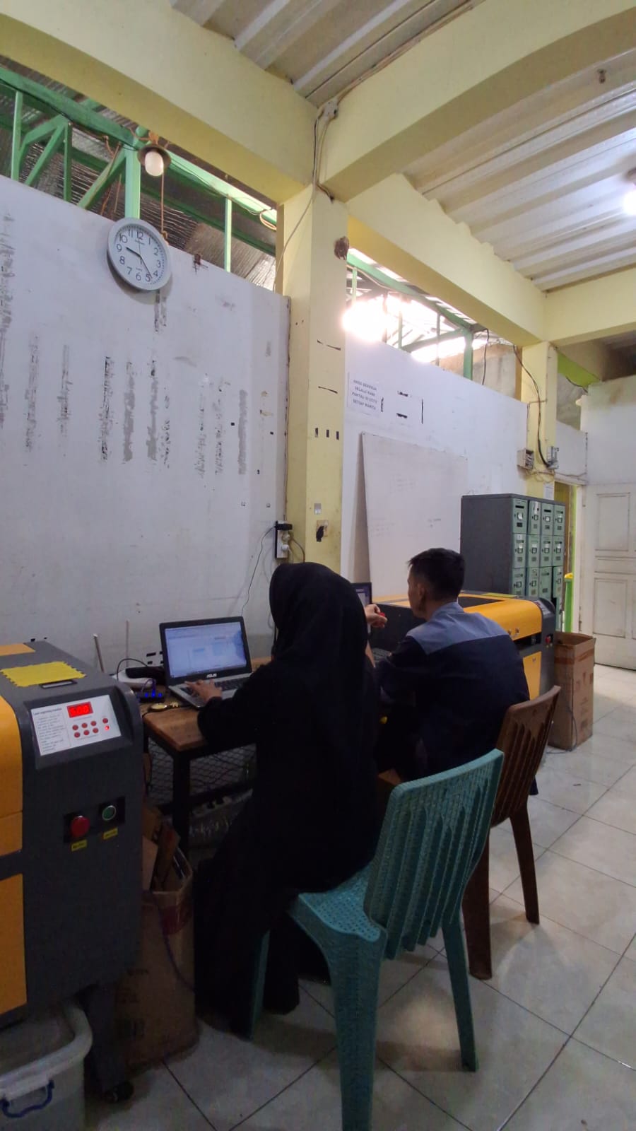 Dua staf mengoperasikan komputer dan mesin produksi BAC