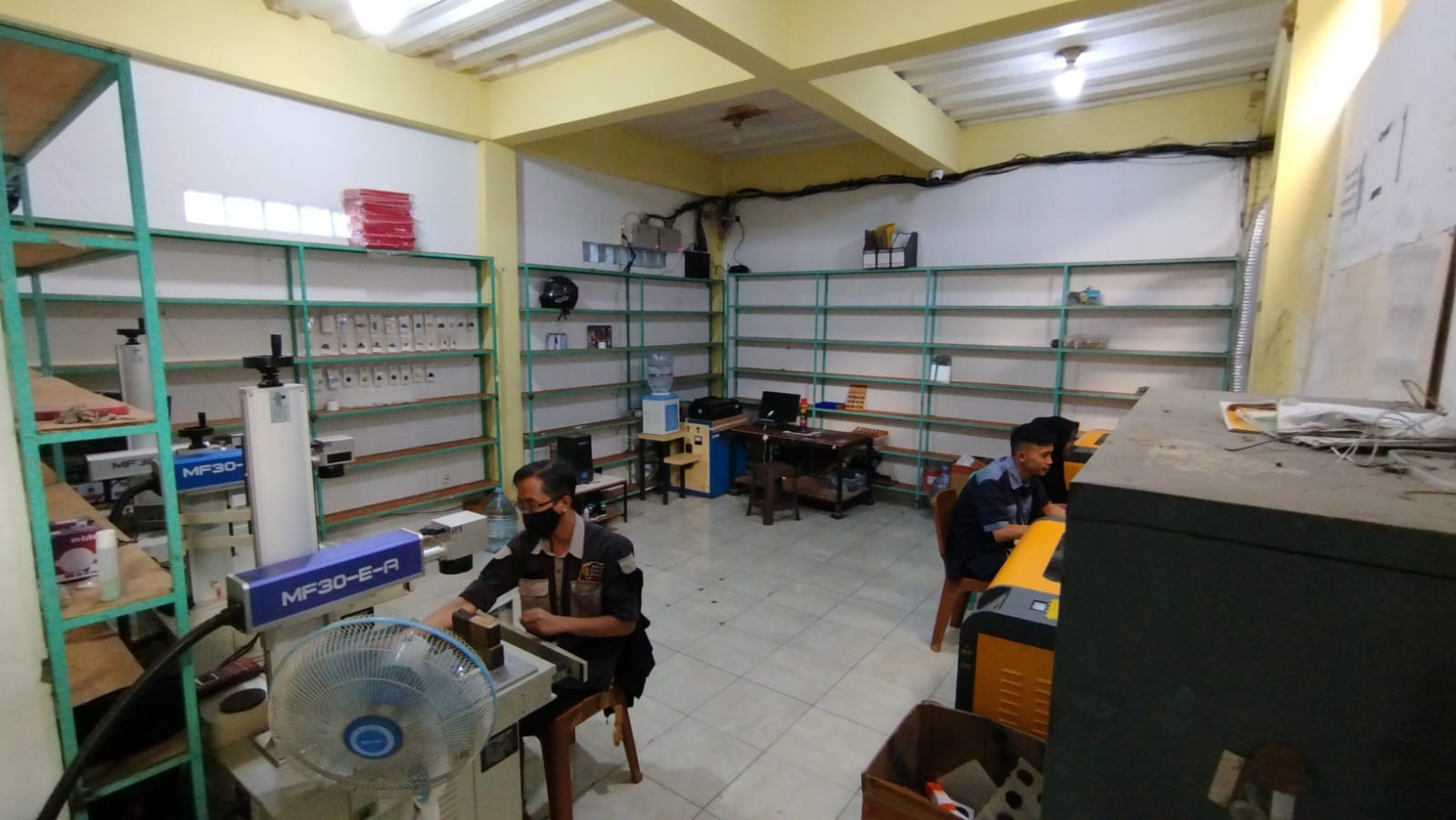 Dua staf bekerja pada mesin di area produksi dan finishing BAC